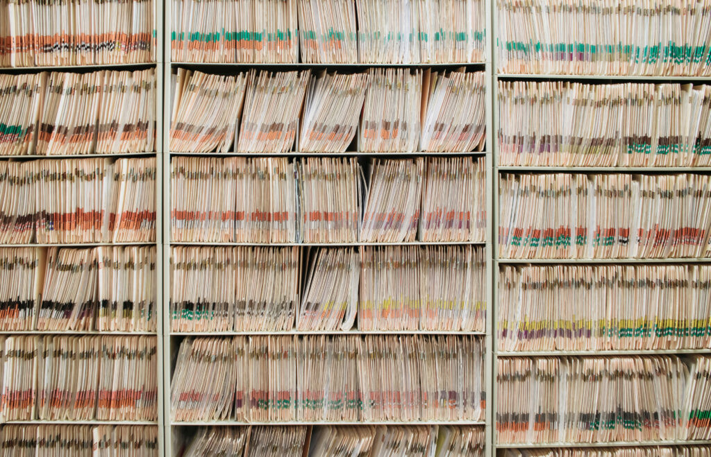 A wall of colour-coded paper files stored in a filing rack