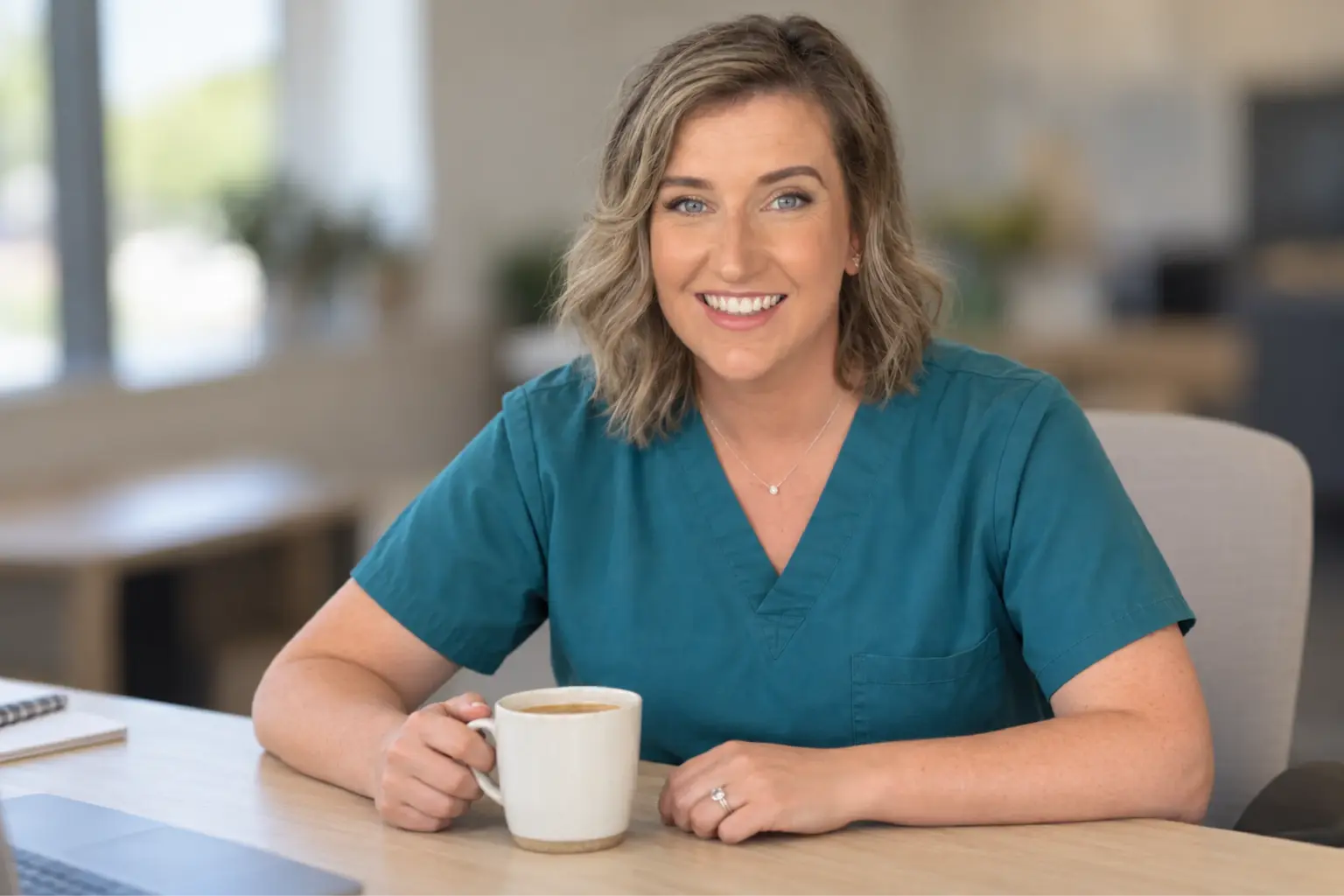 Sarah Jevens, founder of CareReady, in scrubs at her desk